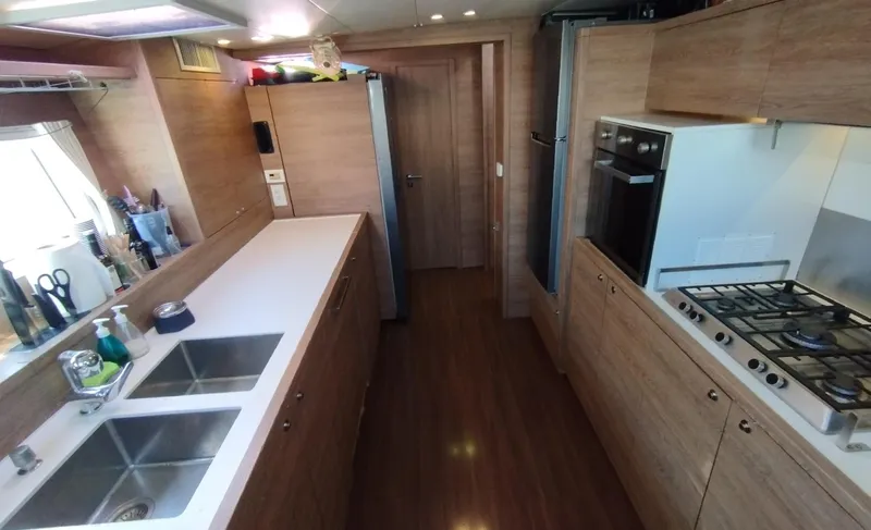 Jarana Yacht Photos Pics Modern kitchen interior of 2012 Lagoon 620 yacht with wood finish and dual sinks.