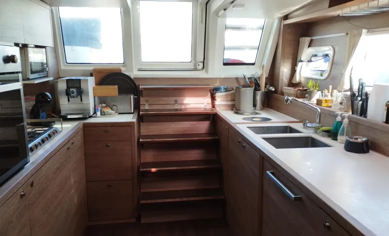 Jarana Yacht Photos Pics Modern kitchen interior of 2012 Lagoon 620 yacht with wooden cabinetry and dual sinks.