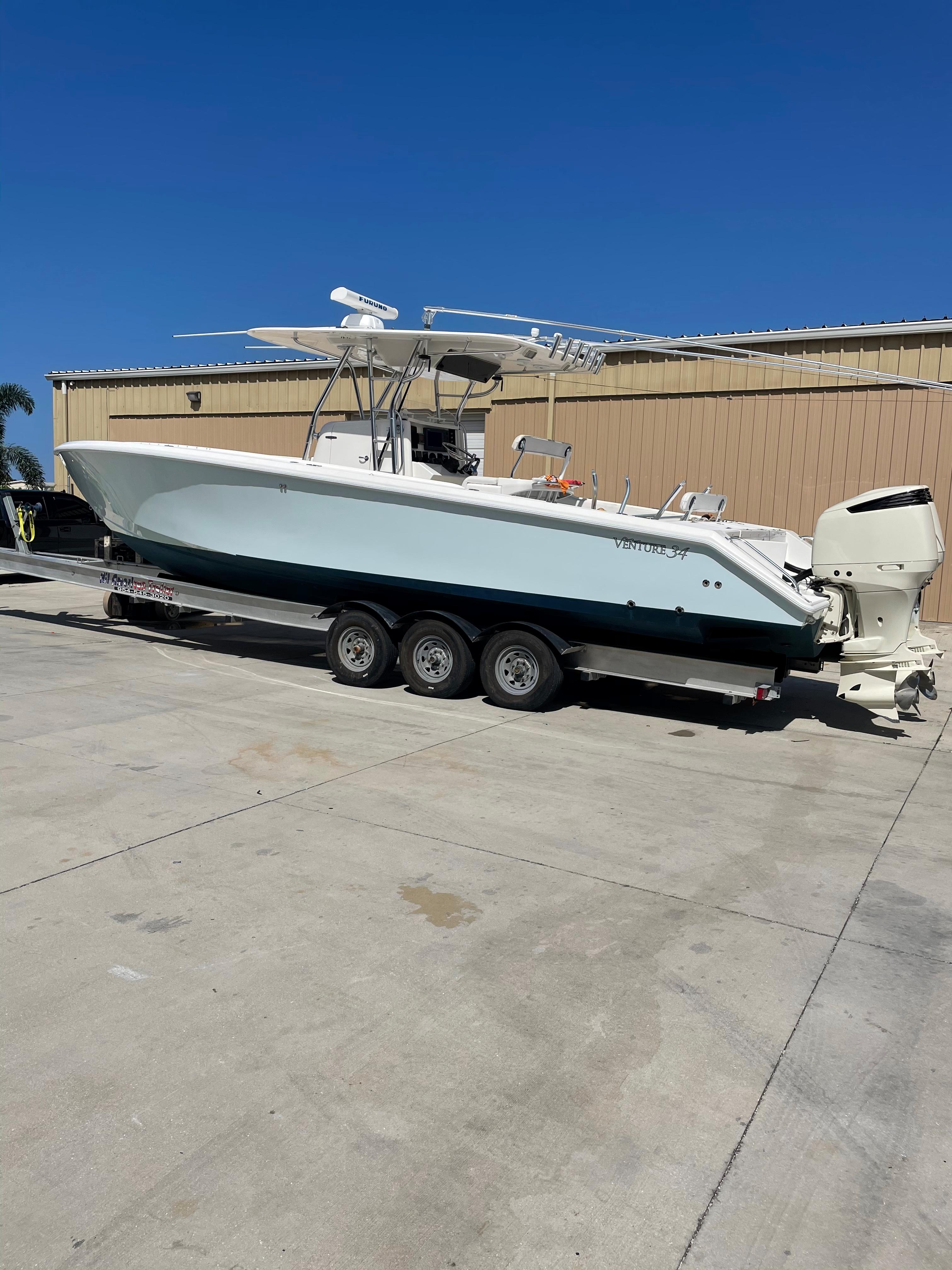 2004 Venture 34 Open boat on trailer, parked outdoors under clear blue sky.