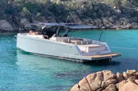 2020 Pardo Yachts 43 anchored in clear turquoise water near rocky shoreline.