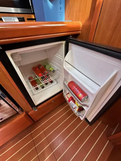  Yacht Photos Pics Mini fridge in 2008 Hunter 38 yacht, stocked with beverages, open on wooden floor.