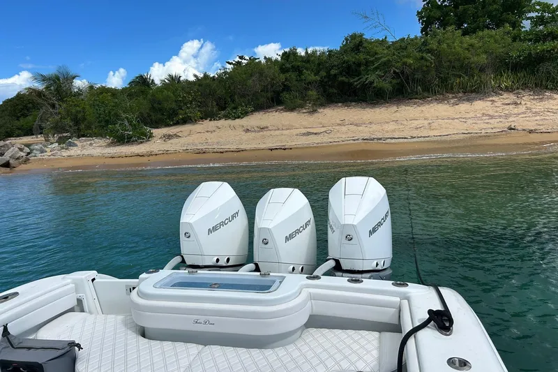 Testa Dura Yacht Photos Pics 2023 Yellowfin 36 Offshore boat with triple Mercury engines near a sandy beach.