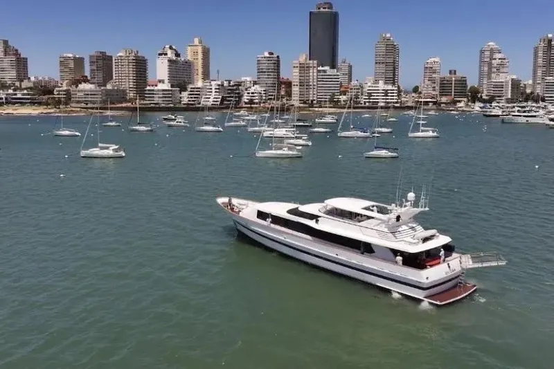  Yacht Photos Pics Luxurious 1987 Lurssen 110 yacht cruising in a bustling harbor with city skyline backdrop.