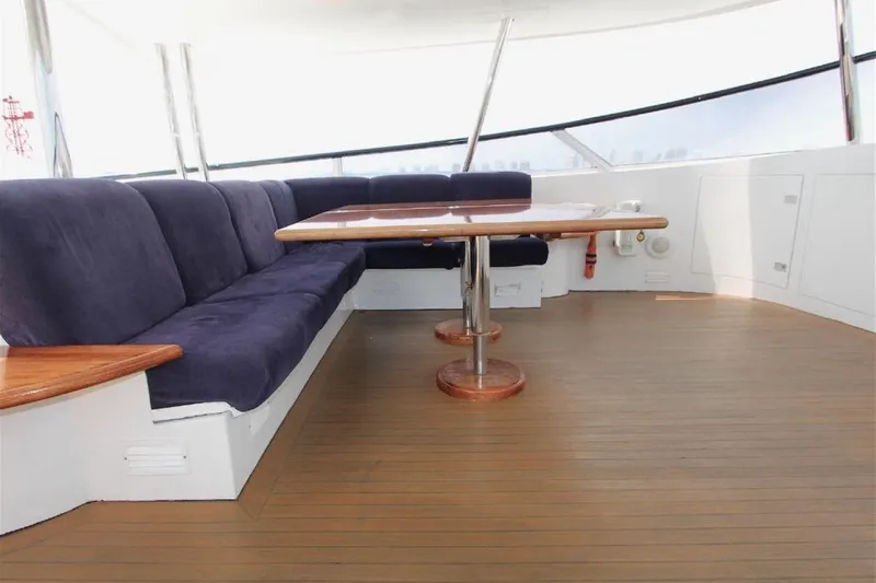  Yacht Photos Pics Luxurious seating area on 1987 Lurssen 110 yacht with wooden table and blue cushions.