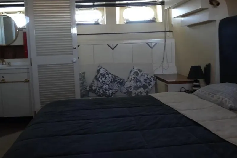  Yacht Photos Pics Cozy bedroom interior of 1987 Lurssen 110 yacht with bed, pillows, and porthole windows.