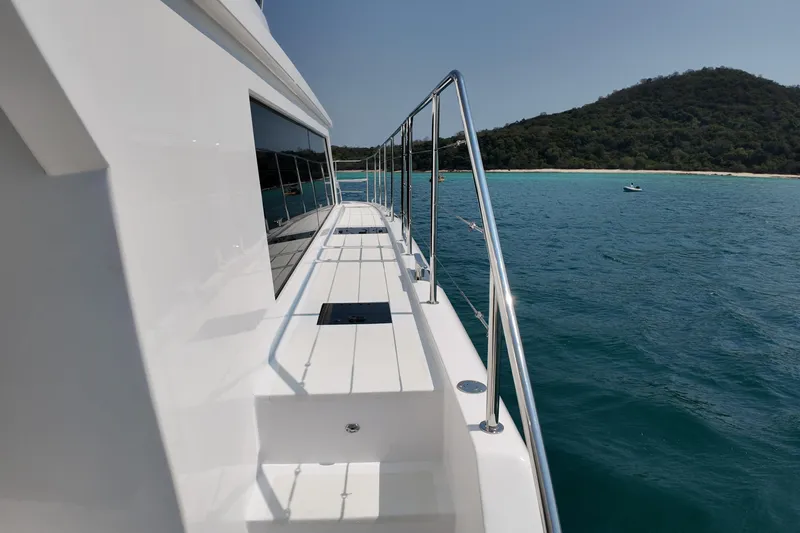  Yacht Photos Pics Side view of 2026 Longreach 58 yacht cruising near a scenic coastline.