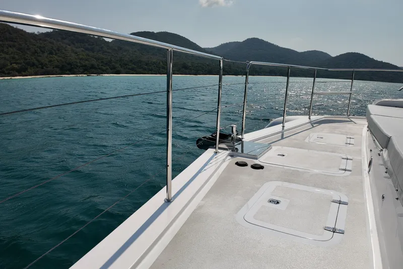  Yacht Photos Pics Deck view of 2026 Longreach 58 yacht cruising near lush, mountainous coastline.
