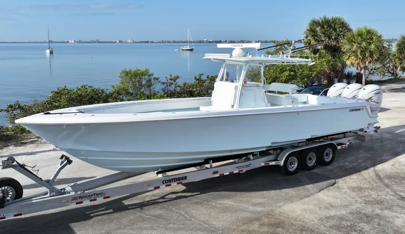  Yacht Photos Pics 2021 Contender 39 ST boat on trailer by waterfront, clear sky, palm trees.