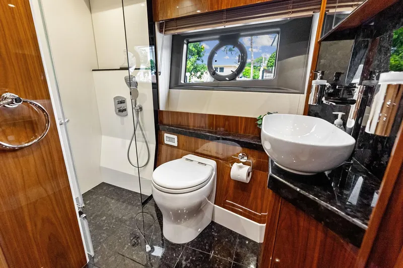 Miller Time Yacht Photos Pics Luxurious bathroom in 2021 Sunseeker Manhattan 52 yacht with modern fixtures and porthole window.