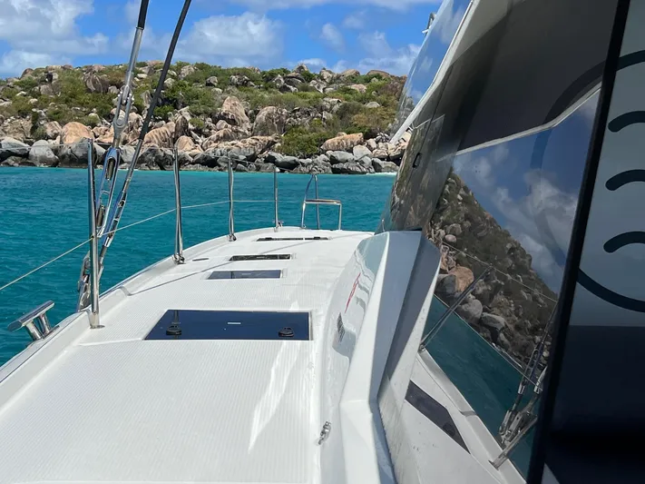 Vienna Yacht Photos Pics 2022 Fountaine Pajot Catamaran Aura 51 sailing near rocky shoreline in clear blue waters.