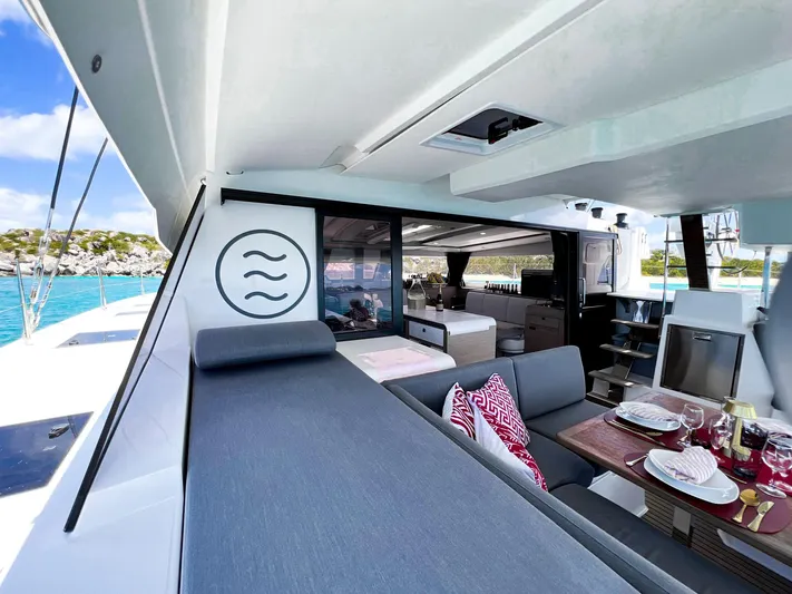 Vienna Yacht Photos Pics 2022 Fountaine Pajot Catamaran Aura 51, luxurious deck with dining area and scenic ocean view.