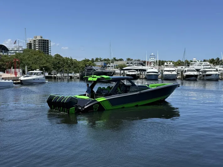 Crypto Excepted! Yacht Photos Pics 2023 Adrenaline 47 boat in marina, vibrant green and black design, surrounded by yachts.
