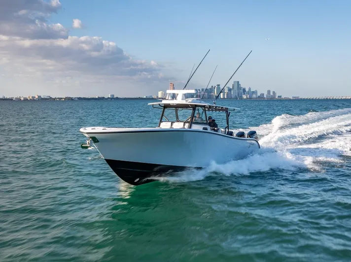  Yacht Photos Pics 2024 Yellowfin 42 boat cruising on open water with city skyline in background.