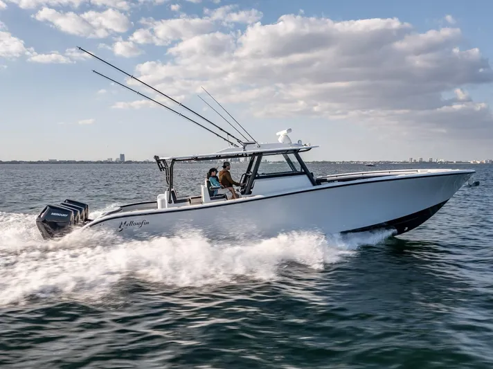  Yacht Photos Pics 2024 Yellowfin 42 boat cruising on open water under a partly cloudy sky.