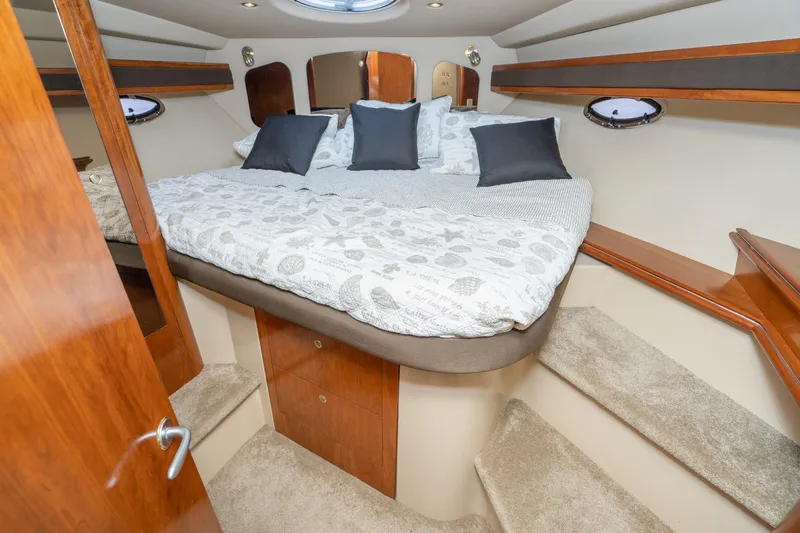 My Jojo Yacht Photos Pics Luxurious cabin interior of 2005 Cruisers Yachts 370 Express with cozy bedding and elegant wood finishes.