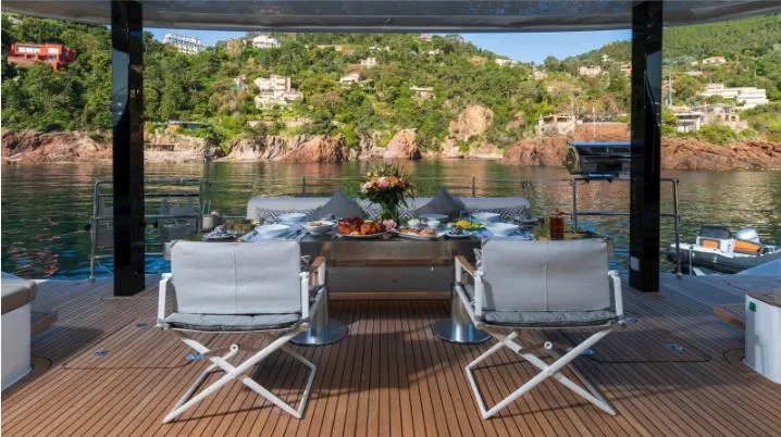 Endless Horizon II Yacht Photos Pics Luxurious Sunreef 80 Sail yacht deck with dining setup, overlooking serene coastal landscape.