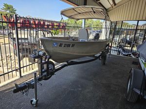 2003 Alumacraft V14 boat on trailer under a canopy, parked near a fence.