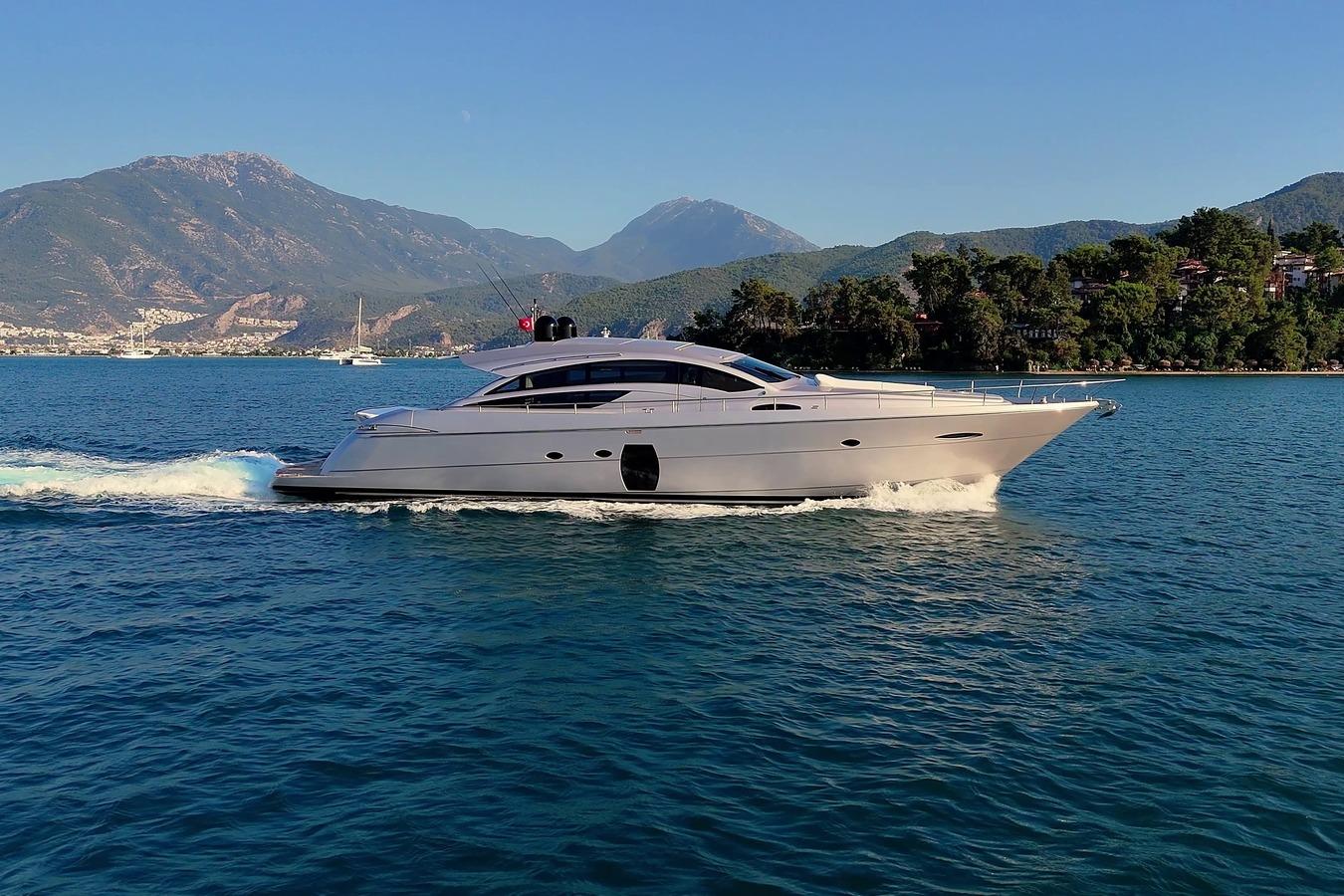 2010 Pershing 72 yacht cruising on blue waters with scenic mountain backdrop.