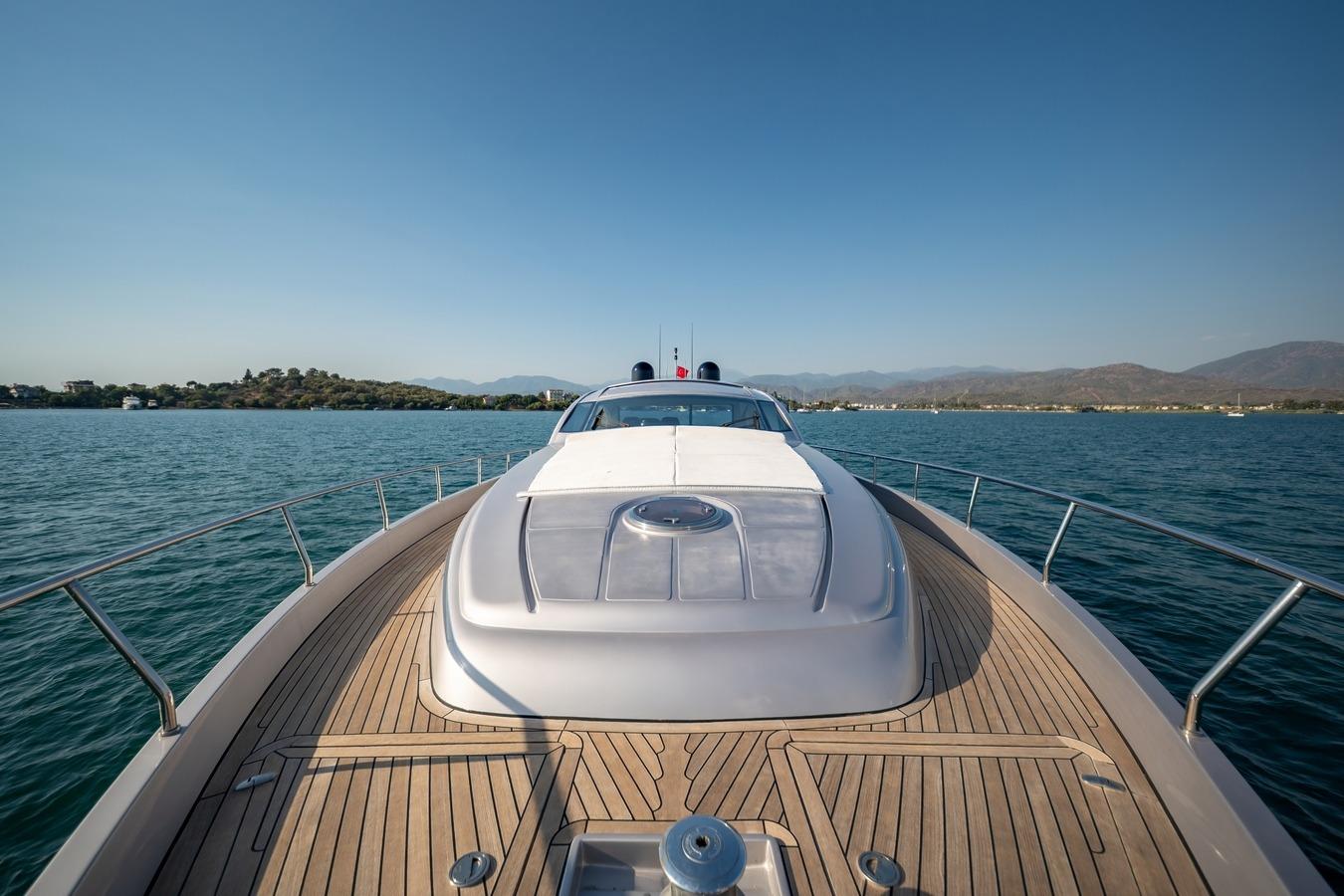 Luxurious 2010 Pershing 72 yacht cruising on serene waters with scenic mountain backdrop.