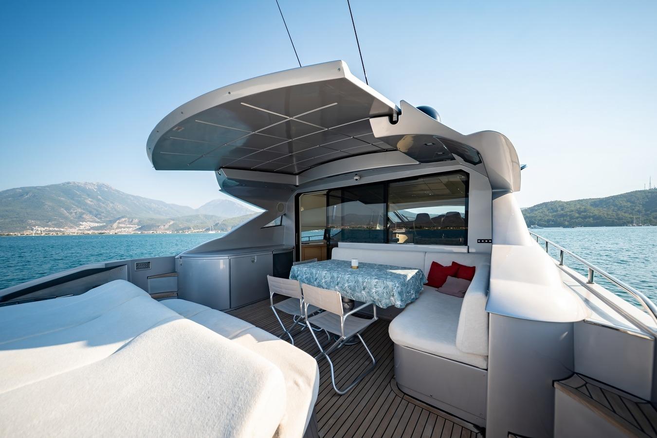 Luxurious 2010 Pershing 72 yacht deck with seating, table, and scenic ocean view.