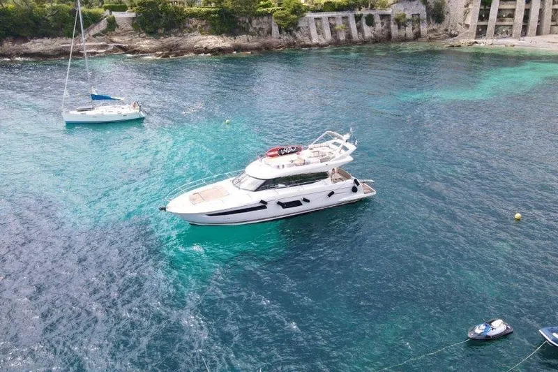  Yacht Photos Pics 2015 Prestige 550 yacht anchored in clear turquoise waters near rocky shoreline.