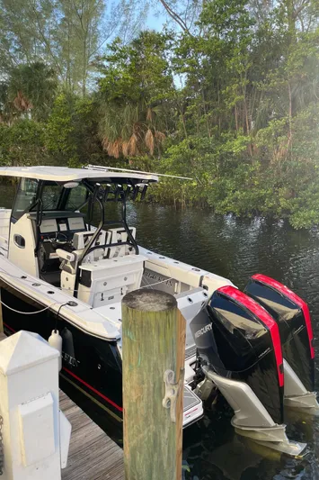  Yacht Photos Pics 2022 Blackfin 272 CC boat docked near lush greenery.