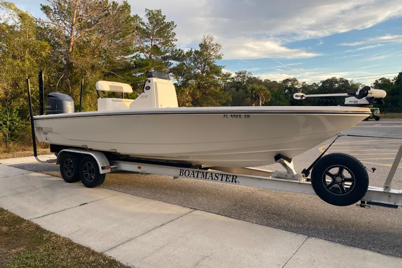  Yacht Photos Pics 2020 Pathfinder 2500 Hybrid boat on trailer in parking lot, surrounded by trees.