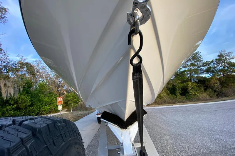  Yacht Photos Pics 2020 Pathfinder 2500 Hybrid boat on trailer, secured with strap, parked near trees.