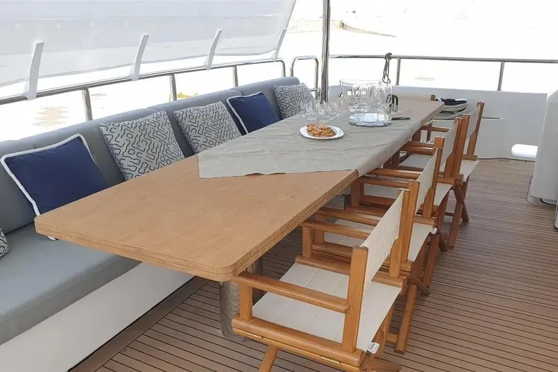  Yacht Photos Pics Outdoor dining area on 2013 Benetti Delfino 93 yacht with wooden table and cushioned seating.