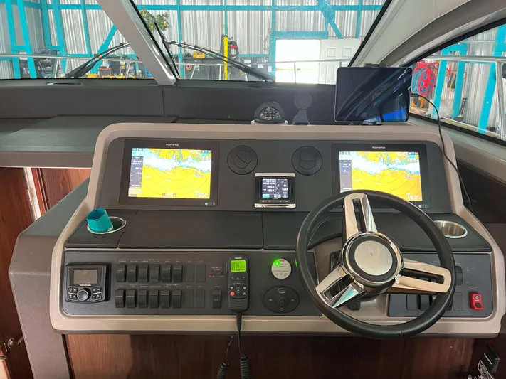 The Good Life Yacht Photos Pics Control panel of a 2018 Sea Ray 400 Sundancer yacht with navigation screens and steering wheel.