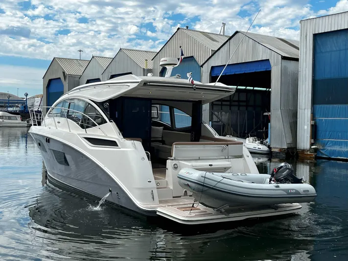 The Good Life Yacht Photos Pics 2018 Sea Ray 400 Sundancer yacht docked near boathouses, featuring sleek design and inflatable dinghy.