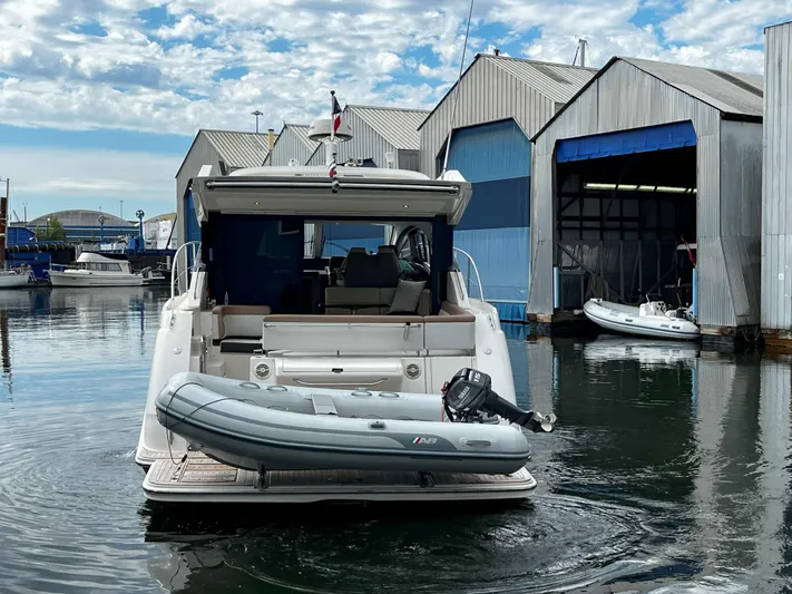 The Good Life Yacht Photos Pics 2018 Sea Ray 400 Sundancer yacht docked with inflatable boat, near marina warehouses.