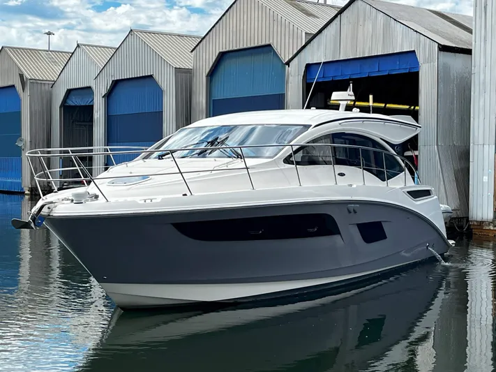 The Good Life Yacht Photos Pics 2018 Sea Ray 400 Sundancer yacht docked near boathouses, reflecting on calm water.