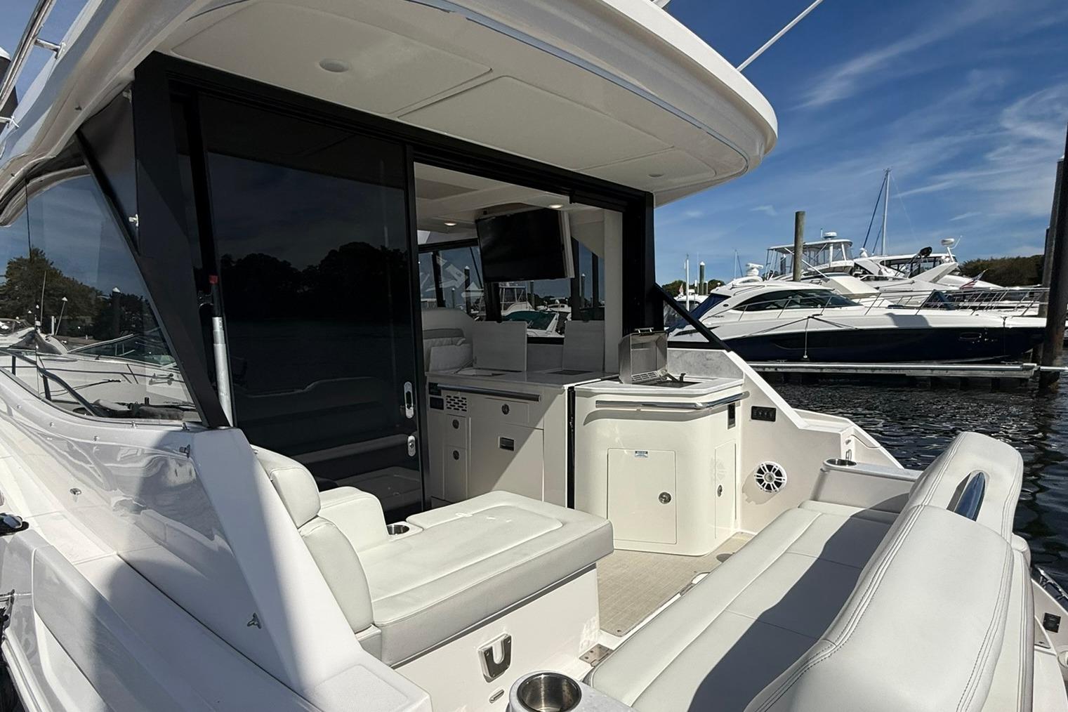 2021 Regal 36 Grande Coupe yacht with luxurious seating and sleek design at a marina.