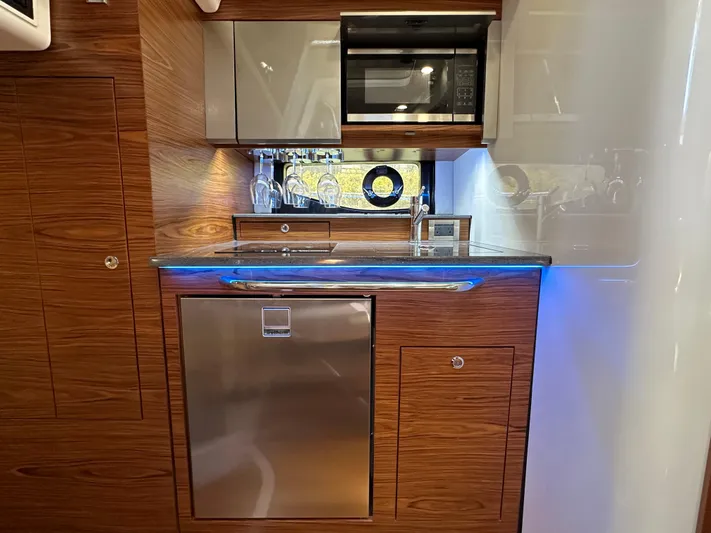 Blue Reeler Yacht Photos Pics 2023 Boston Whaler 405 Conquest kitchen with wood cabinetry, stainless steel appliances, and modern fixtures.