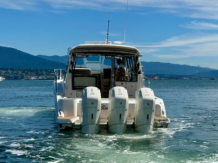 Blue Reeler Yacht Photos Pics 2023 Boston Whaler 405 Conquest boat on water, rear view with four engines.