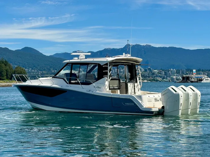 Blue Reeler Yacht Photos Pics 2023 Boston Whaler 405 Conquest boat on water with scenic mountain backdrop.