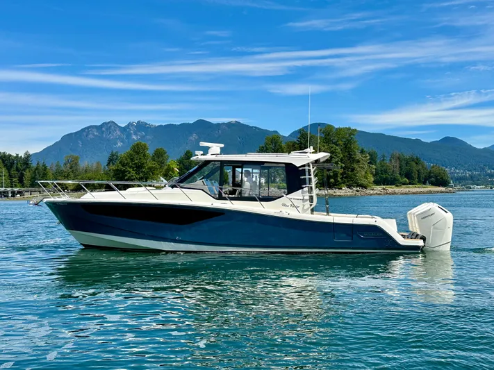 Blue Reeler Yacht Photos Pics 2023 Boston Whaler 405 Conquest boat on a scenic lake with mountains in the background.