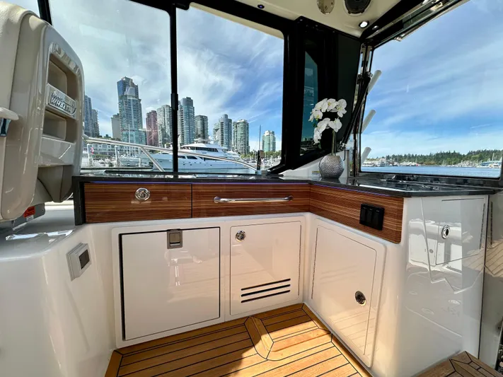 Blue Reeler Yacht Photos Pics 2023 Boston Whaler 405 Conquest interior with city skyline view, featuring sleek cabinetry and wood flooring.