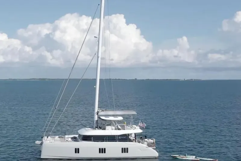 So Gnar Yacht Photos Pics 2022 Sunreef 60 Sail catamaran on calm ocean waters under a cloudy sky.