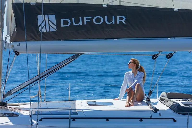 Dufour 530 In Annapolis Yacht Photos Pics Woman relaxing on a 2024 Dufour 530 sailboat under clear blue skies.
