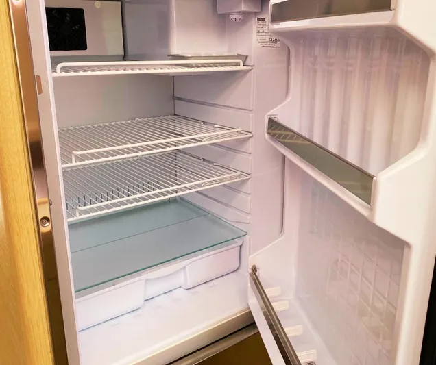 Dufour 530 In Annapolis Yacht Photos Pics Empty refrigerator in a 2024 Dufour 530 yacht, featuring multiple shelves and door compartments.