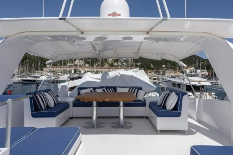  Yacht Photos Pics Luxurious 1995 Codecasa 24 yacht deck with blue seating and wooden table in marina.