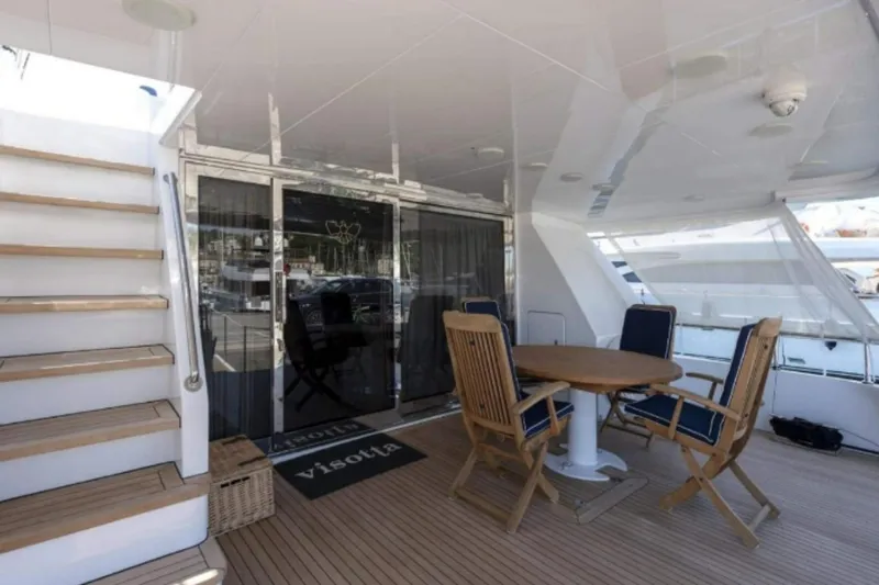  Yacht Photos Pics Luxury yacht deck with wooden furniture, stairs, and glass doors; Codecasa 24, 1995 model.