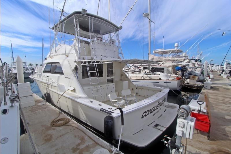 1994 Bertram 50 Convertible yacht docked at marina under clear blue sky.