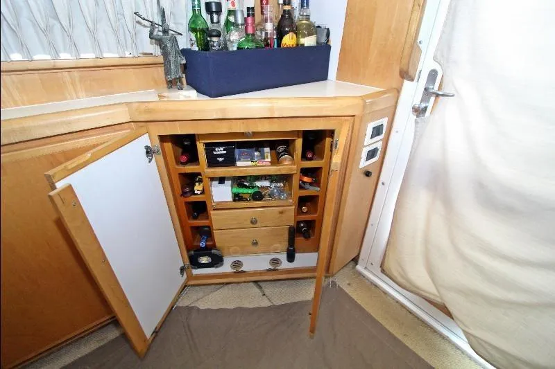 Yacht Photos Pics Bar cabinet with open doors on a 1994 Bertram 50 Convertible yacht, showcasing liquor bottles.