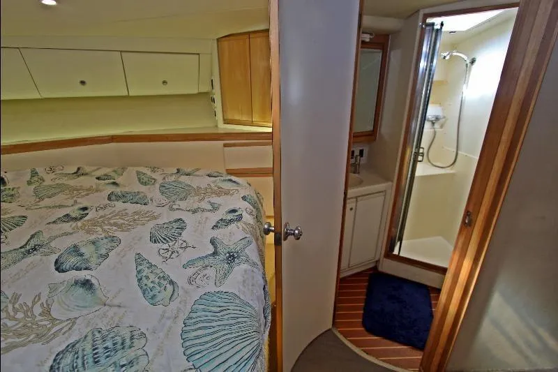  Yacht Photos Pics 1994 Bertram 50 Convertible yacht interior with bedroom and bathroom, featuring nautical-themed bedding.