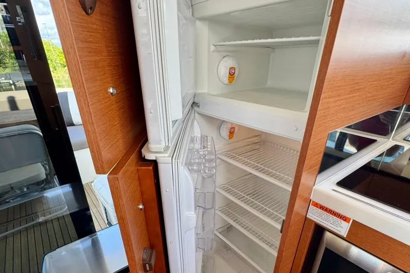 My Three Es Yacht Photos Pics Open fridge inside 2016 Prestige 500 S yacht, featuring wooden cabinetry and modern design.