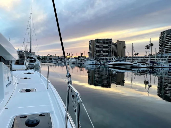 Ariella Yacht Photos Pics Lagoon 42 catamaran in marina at sunset, reflecting calm waters and city skyline, 2021 model.