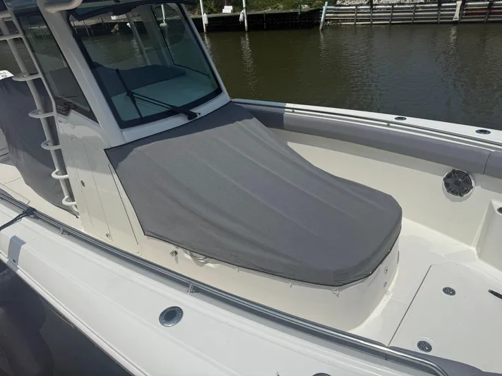  Yacht Photos Pics 2024 Boston Whaler 330 Outrage boat with covered seating area, docked by the water.